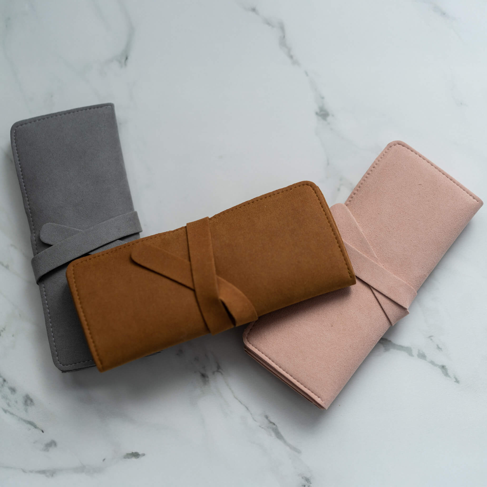 Trio of suede travel jewelry rolls stacked diagonally—ideal for secure and stylish packing