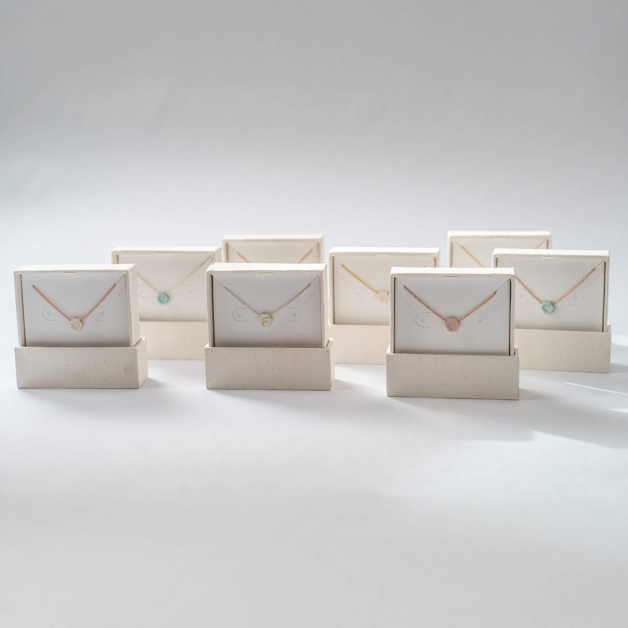 Group of handmade porcelain necklaces with initials, perfect for Mother's Day gifts, shown in Almundrella packaging.