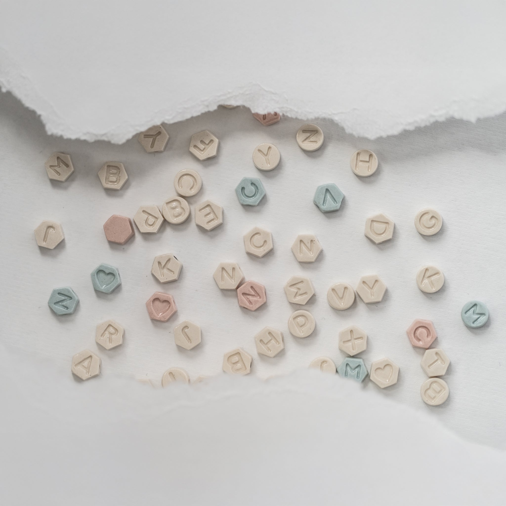 Flatlay of porcelain letter charms in soft pastel tones—perfect for personalized jewelry