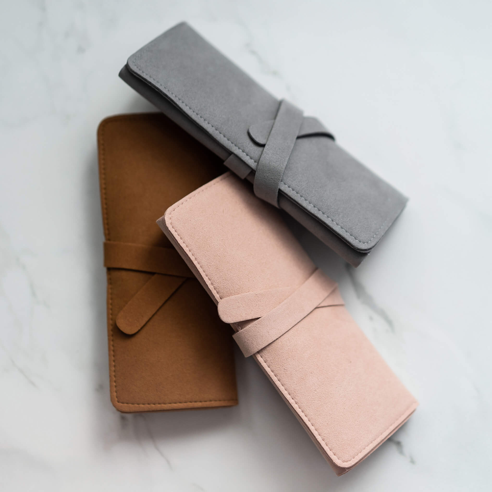 Trio of suede travel jewelry rolls stacked diagonally—ideal for secure and stylish packing
