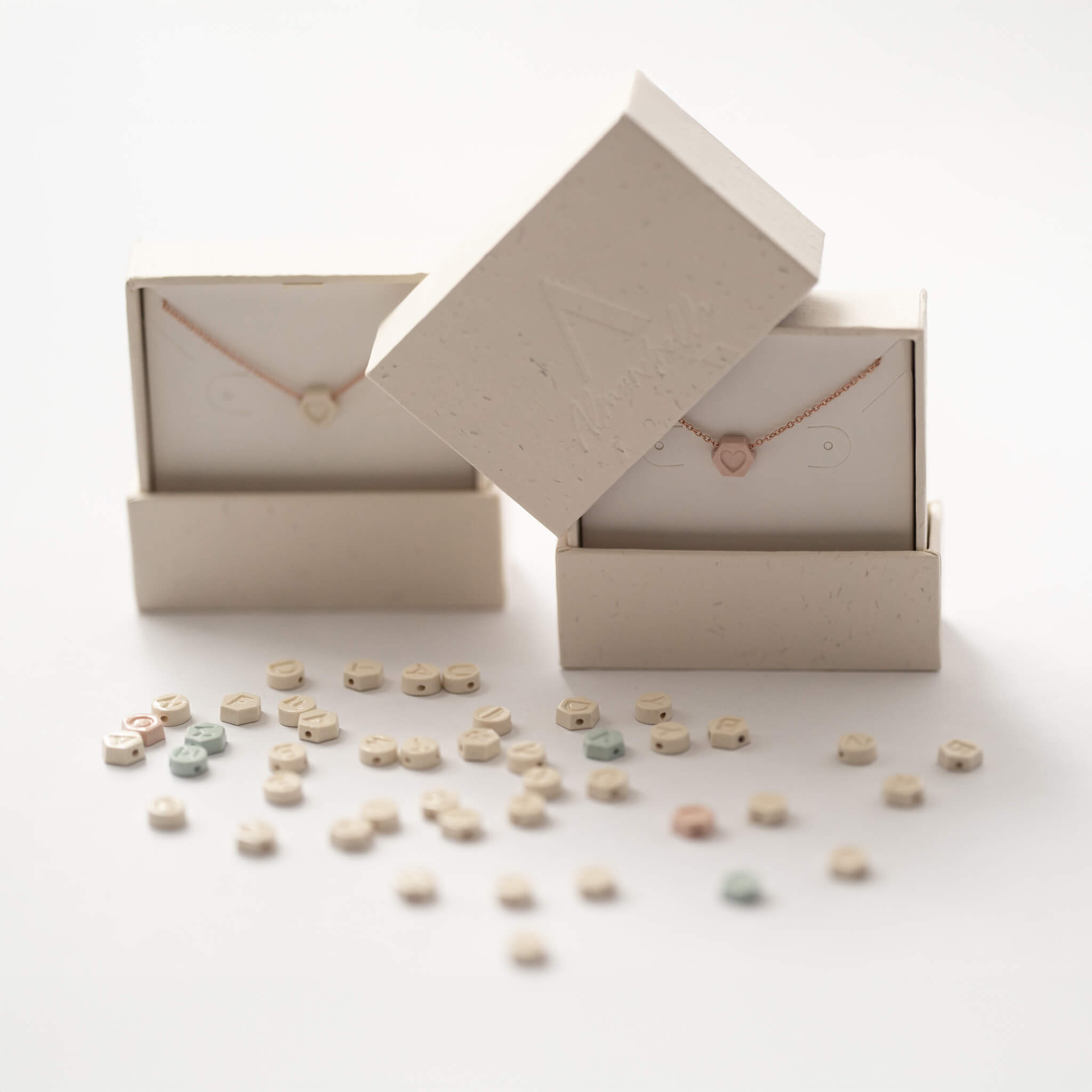 Two personalized porcelain necklaces surrounded by letter charms.